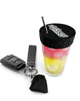 NightCap portable drink cover keychain displayed beside a protected cocktail with a reusable straw for drink spiking prevention.