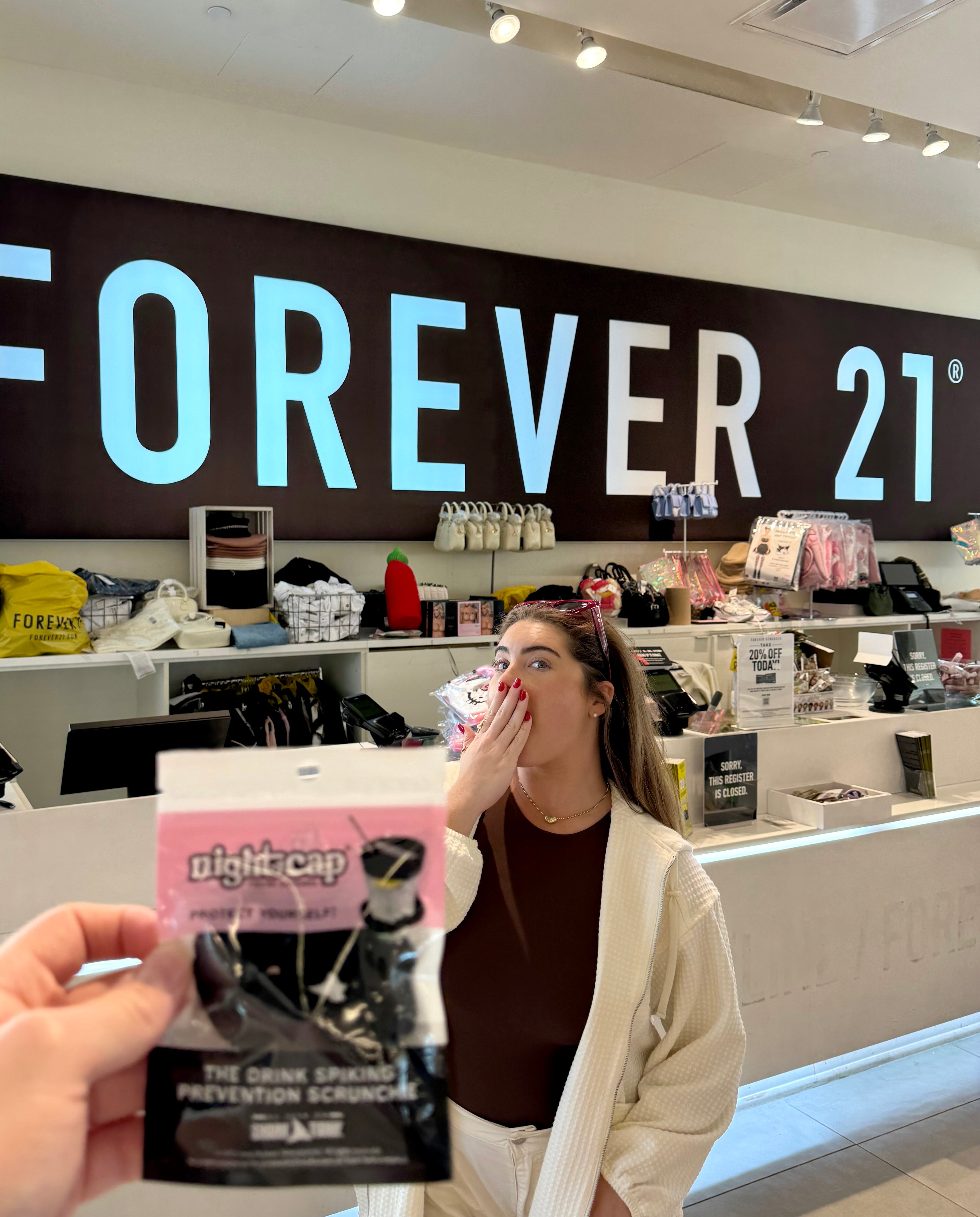 Founder holding a nightcap scrunchie in front of a Forever 21 store